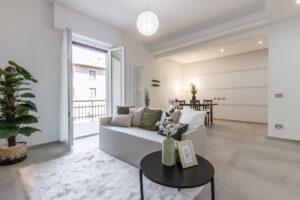 Il "dopo" di una ristrutturazione a Parma: Mario Conte di CMG Crea Casa mostra il soggiorno trasformato in un open space moderno con controsoffitto, faretti a LED e pavimento in gres.