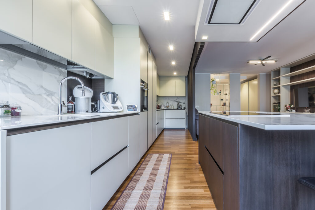 Cucina moderna con isola e salotto, esempio del lavoro di un'impresa edile strutturata a Parma come CMG.