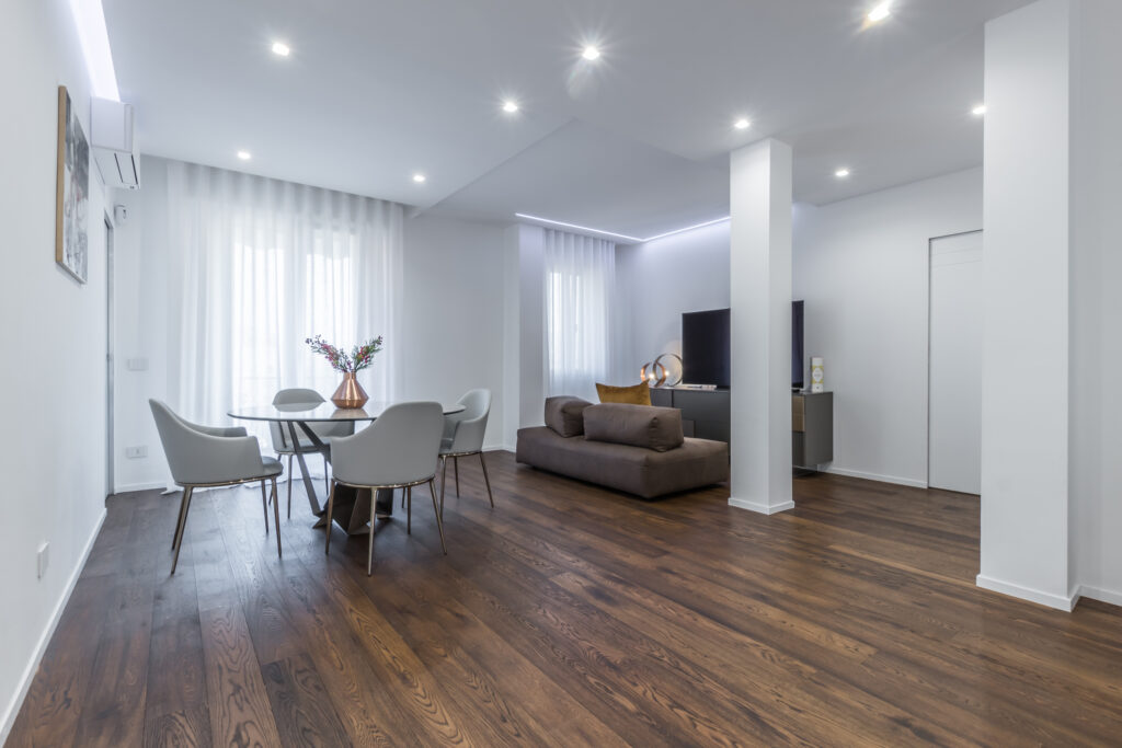 Soggiorno open space a Parma con zona pranzo e relax, esempio di progetto integrato dove layout e illuminazione sono studiati per la massima funzionalità.